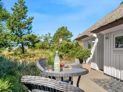 a table and chairs on a patio with a bottle of wine at Holiday Home Pihla - 1-1km from the sea by Interhome in Fjerritslev