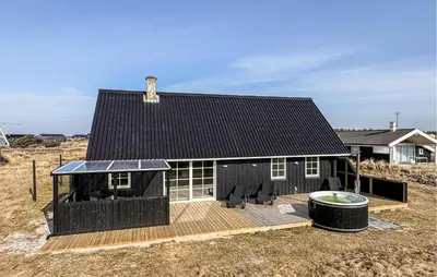 a house with a black roof and a wooden deck at 2 Bedroom Stunning Home In Harboøre in Harboør