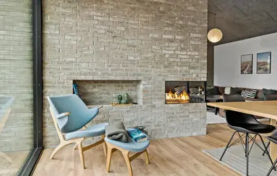 a living room with a brick fireplace and blue chairs at 4 Bedroom Pet Friendly Home In Blokhus in Blokhus