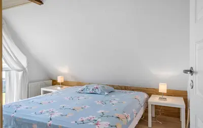 a bedroom with a bed with a blue comforter and two tables at 4 Bedroom Nice Home In Harboøre in Harboør