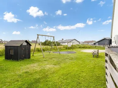 a playground in a yard with a swing at Apartment Hansa - 300m from the sea by Interhome in Torsted
