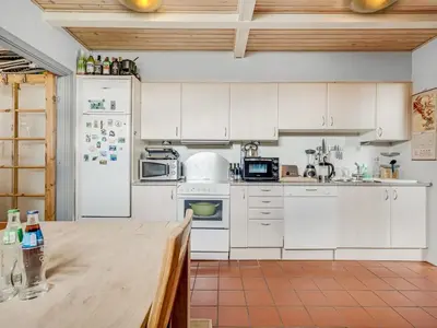 a kitchen with white cabinets and a white refrigerator at Apartment Hansa - 300m from the sea by Interhome in Torsted