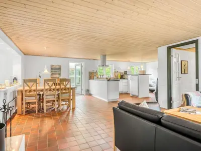 a living room with a couch and a table and a kitchen at Holiday Home Lyra - 500m to the fjord by Interhome in Øsløs