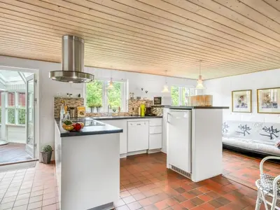 a kitchen with white cabinets and a wooden ceiling at Holiday Home Lyra - 500m to the fjord by Interhome in Øsløs