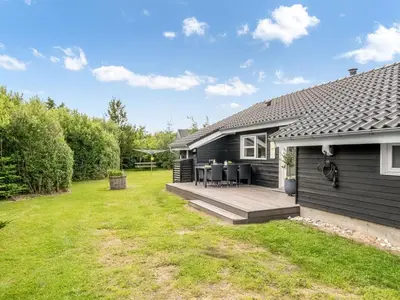 a black house with a deck and a yard at Holiday Home Lissi - 3-5km from the sea by Interhome in Brovst