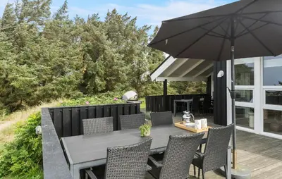 a patio with an umbrella and a table and chairs at Awesome Home In Løkken With Kitchen in Løkken