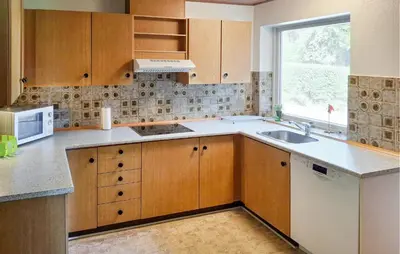 a kitchen with wooden cabinets and a sink and a window at 2 Bedroom Stunning Home In Erslev in Erslev