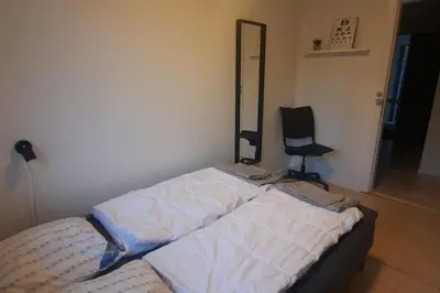 a bed in a room with a mirror and a chair at Centralt beliggende hyggeligt byhus med 8 sovepladser 130m2 med pejs in Holstebro