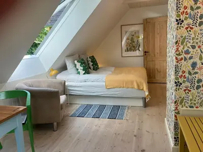 a small attic bedroom with a bed and a chair at Krogsgaarden B&B in Nibe