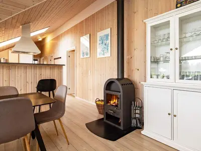 a fireplace in a living room with a table and chairs at 14 person holiday home in Højslev in Sundstrup