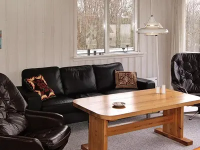 a living room with a black couch and a wooden table at 8 person holiday home in Hurup Thy-By Traum in Sindrup