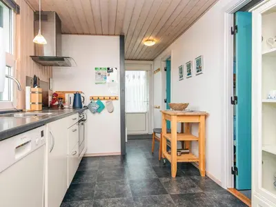 a kitchen with white cabinets and a table at Seaside Escape with Swing in Vrist