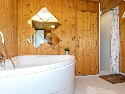 a bathroom with a white tub and wooden walls at Family-friendly Retreat near Beach - By Traum Ferienwohnungen in Lild Strand