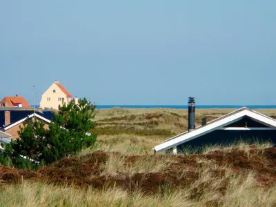 a house in the middle of a field of tall grass at Family-friendly Retreat near Beach - By Traum Ferienwohnungen in Lild Strand