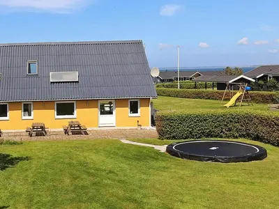 a yellow house with a playground and a trampoline at 10 person holiday home in Vinderup-By Traum in Vinderup