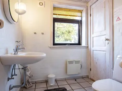 a bathroom with a sink and a window and a toilet at 12 person holiday home in Pandrup-By Traum in Rødhus