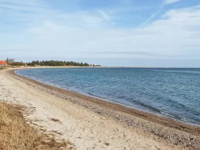a beach with the ocean and trees in the distance at 4 person holiday home in Lemvig-By Traum in Lemvig