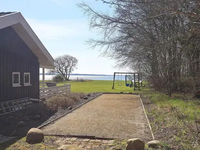 a playground next to a house with a swing at Fjordview Retreat with Spa - By Traum Ferienwohnungen in Sillerslev