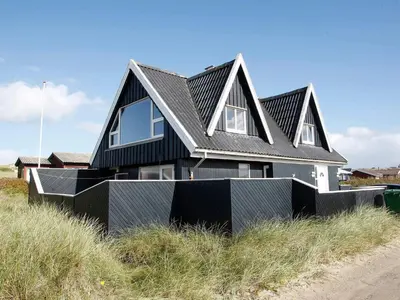 a house with a black roof on a beach at Panoramic Sea View Retreat - By Traum Ferienwohnungen in Blokhus