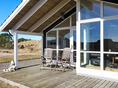 two chairs and a table on a porch with windows at Tranquil Retreat in Klitmoller - By Traum Ferienwohnungen in Klitmøller