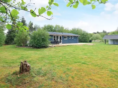 a blue house in the middle of a yard at 5 person holiday home in Thyholm-By Traum in Sindrup