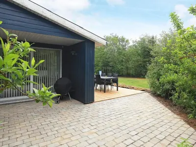 a blue shed with a table and chairs on a patio at 5 person holiday home in Thyholm-By Traum in Sindrup