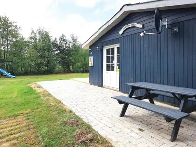 a picnic table sitting in front of a blue building at 5 person holiday home in Thyholm-By Traum in Sindrup