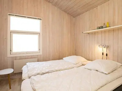 a bedroom with a large bed and a window at 6 person holiday home in Blokhus in Blokhus