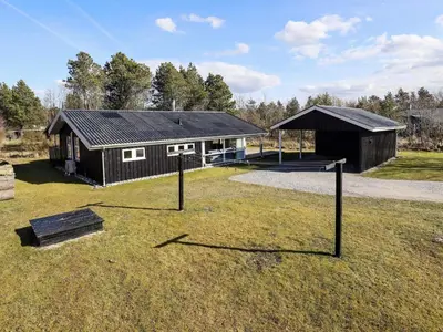 a black house with a tennis court in front of it at 6 person holiday home in Blokhus in Blokhus
