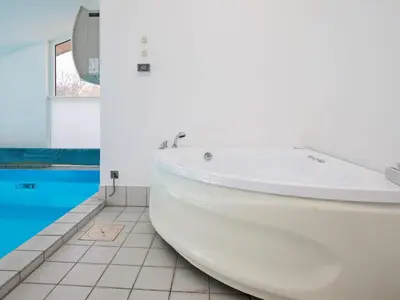 a white bath tub in a bathroom with a pool at Luxury Retreat with Pool - By Traum Ferienwohnungen in Torup Strand