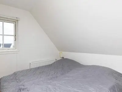 a white bedroom with a bed and a window at 6 person holiday home in Blokhus-By Traum in Blokhus