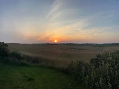 a sunset in a field with the sun in the distance at 4 person holiday home in Lemvig-By Traum in Trans