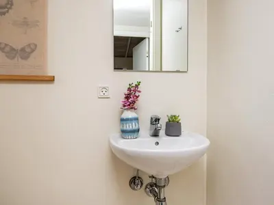 a bathroom sink with a mirror and a vase with flowers at 8 person holiday home in Ulfborg in Thorsminde