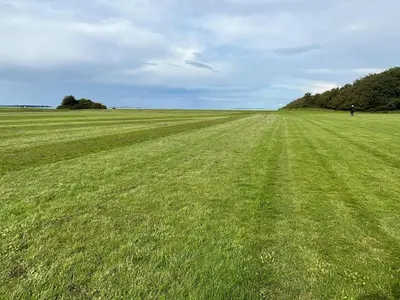 a large field of green grass with a person in the distance at 10 person holiday home in Roslev in Flovtrup