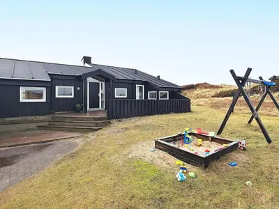 a black house with a sandbox in front of it at Luxury Beachfront Retreat - By Traum Ferienwohnungen in Rødhus