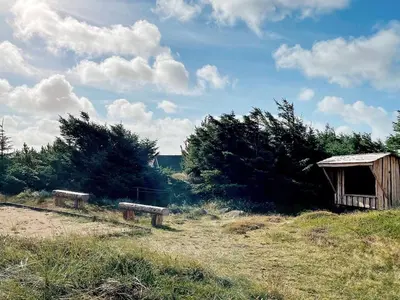 a wooden shed and two benches in a field at Luxury Pool Retreat by Sea - By Traum Ferienwohnungen in Harboør