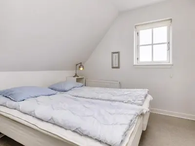 a white bed with blue pillows in a bedroom at 6 person holiday home in Blokhus-By Traum in Blokhus