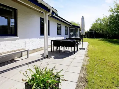 a patio with tables and an umbrella and a lawn at 8 person holiday home in Fjerritslev-By Traum in Slettestrand