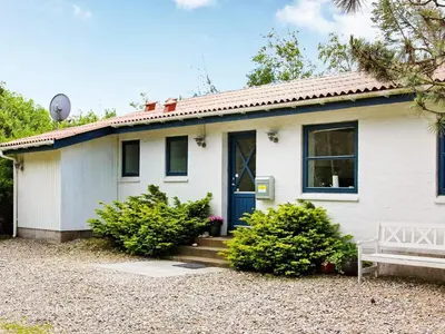 a white house with a blue door and a bench at 8 person holiday home in Fjerritslev-By Traum in Slettestrand