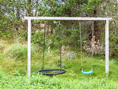 a swing in the grass in a field at Luxury Pool House near Beach - By Traum Ferienwohnungen in Klitmøller