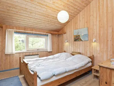 a bed in a wooden room with a window at Luxury Pool House near Beach - By Traum Ferienwohnungen in Klitmøller