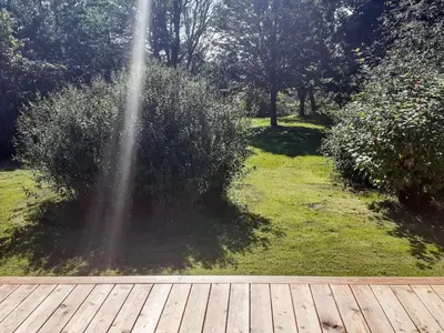 a wooden deck in a garden with a fountain at Seaside Rustic Retreat - By Traum Ferienwohnungen in Flovtrup