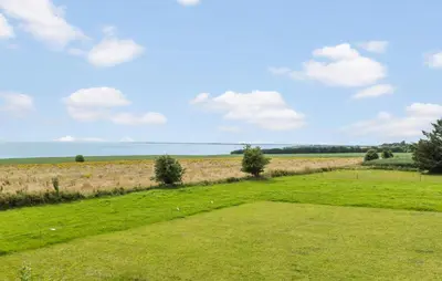 a field of green grass with the ocean in the background at Cozy Home In Øster Assels With Wifi in Øster Assels