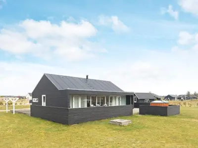 a black house sitting on top of a grass field at 8 person holiday home in Brovst-By Traum in Brovst