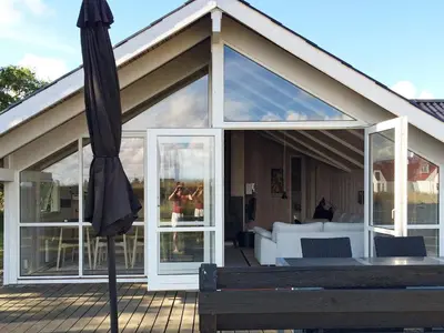 an umbrella sitting on a deck next to a house at Cozy Retreat with Spa - By Traum Ferienwohnungen in Stenbjerg