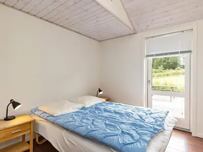 a bedroom with a bed with blue sheets and a window at 8 person holiday home in Skals in Hjarbæk