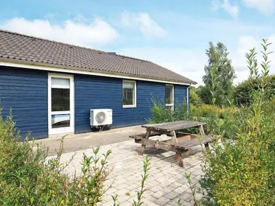 a picnic table next to a blue building with a table at 8 person holiday home in Skals in Hjarbæk