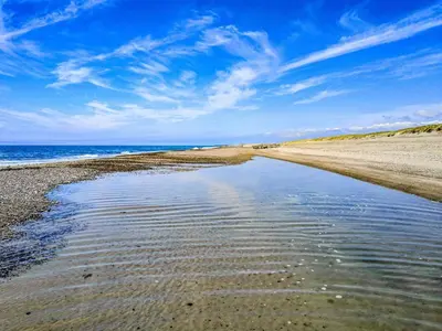 a beach with a reflection of the sky in the water at 6 person holiday home in Harboøre-By Traum in Harboør