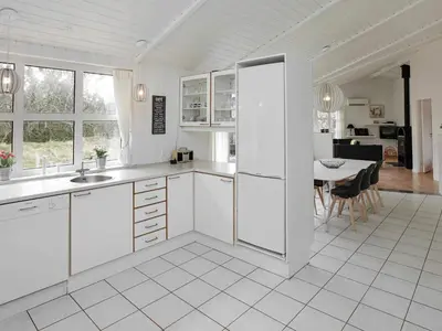 a kitchen with white cabinets and a table with chairs at Luxury Retreat with Pool - By Traum Ferienwohnungen in Grønhøj