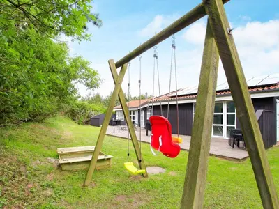 a swing in a yard next to a house at Luxury Retreat with Pool - By Traum Ferienwohnungen in Grønhøj